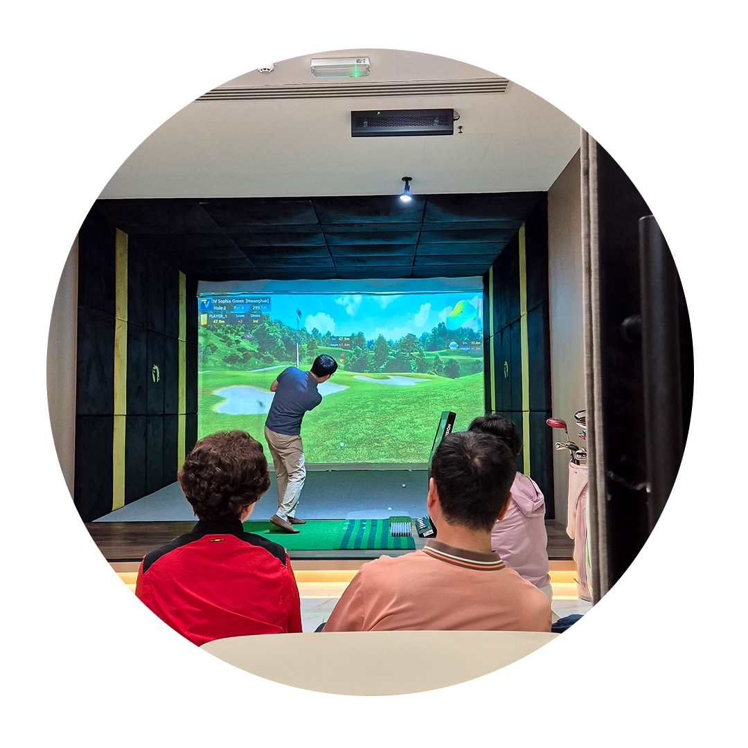 People watching a man play golf on an indoor golf simulator.