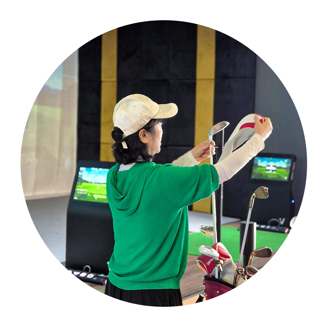 Woman selecting a golf club from her bag at an indoor golf simulator.